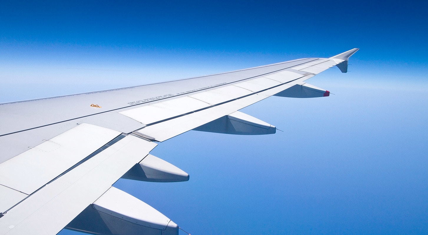 Aerial view of an airplane wing against a clear blue sky.